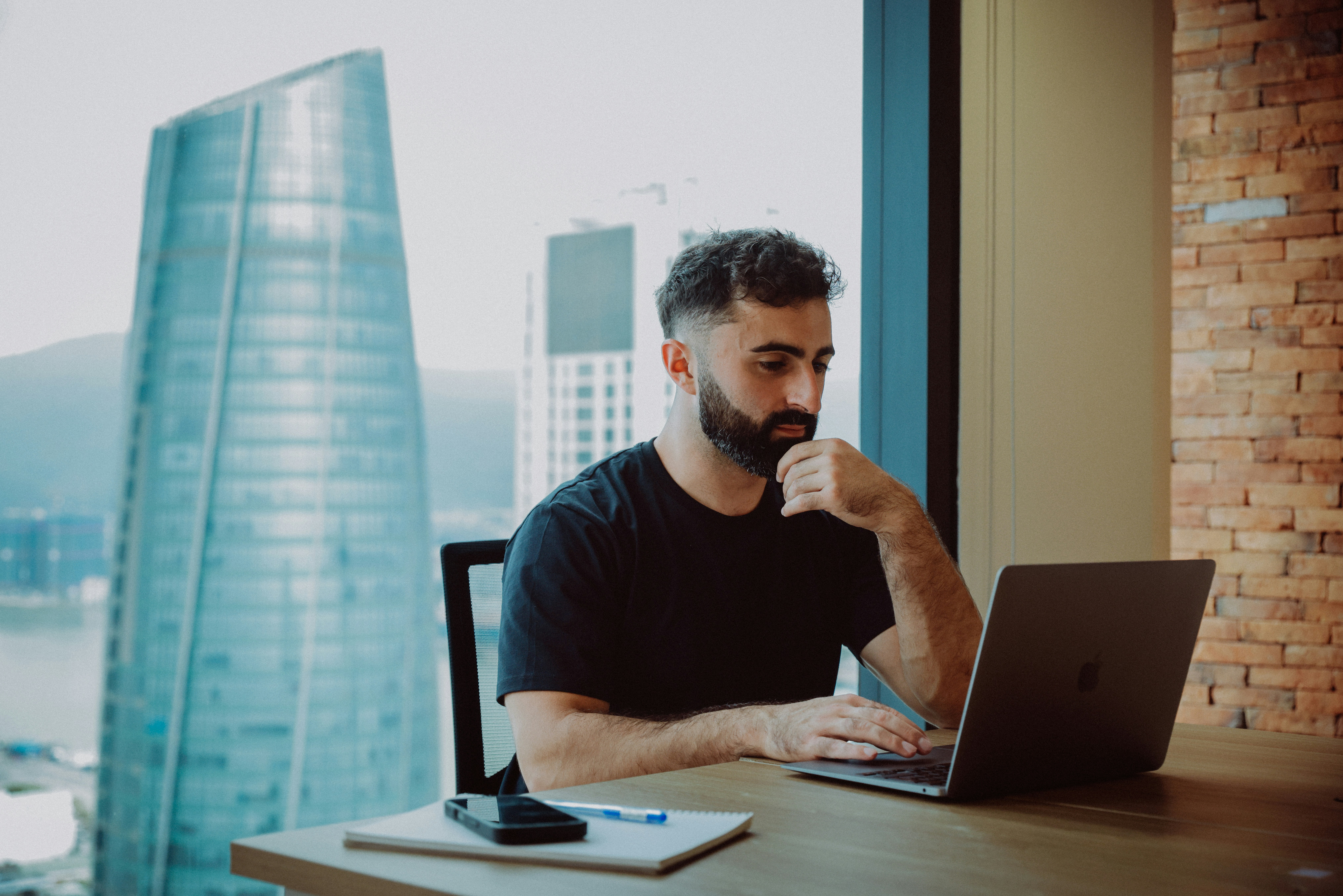 James Kemp reviewing strategy notes on a laptop with city skyline behind him